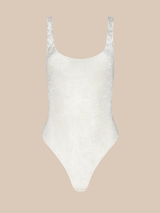 The Kalea Mesh Bodysuit, a white velvet sleeveless piece featuring a scoop neckline and high-cut leg openings—ideal as a lightweight layer—is displayed on a plain beige background.