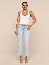 A woman stands facing forward against a plain white background, wearing the Cole Scoopneck Tank, light blue jeans, a tan belt, and nude heels. One hand rests on her hip while the other hangs by her side.