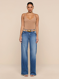 A person stands facing forward, wearing the Wrenna Racerback Bodysuit in tan, paired with blue wide-leg jeans, a brown belt, and sandals against a plain white background.