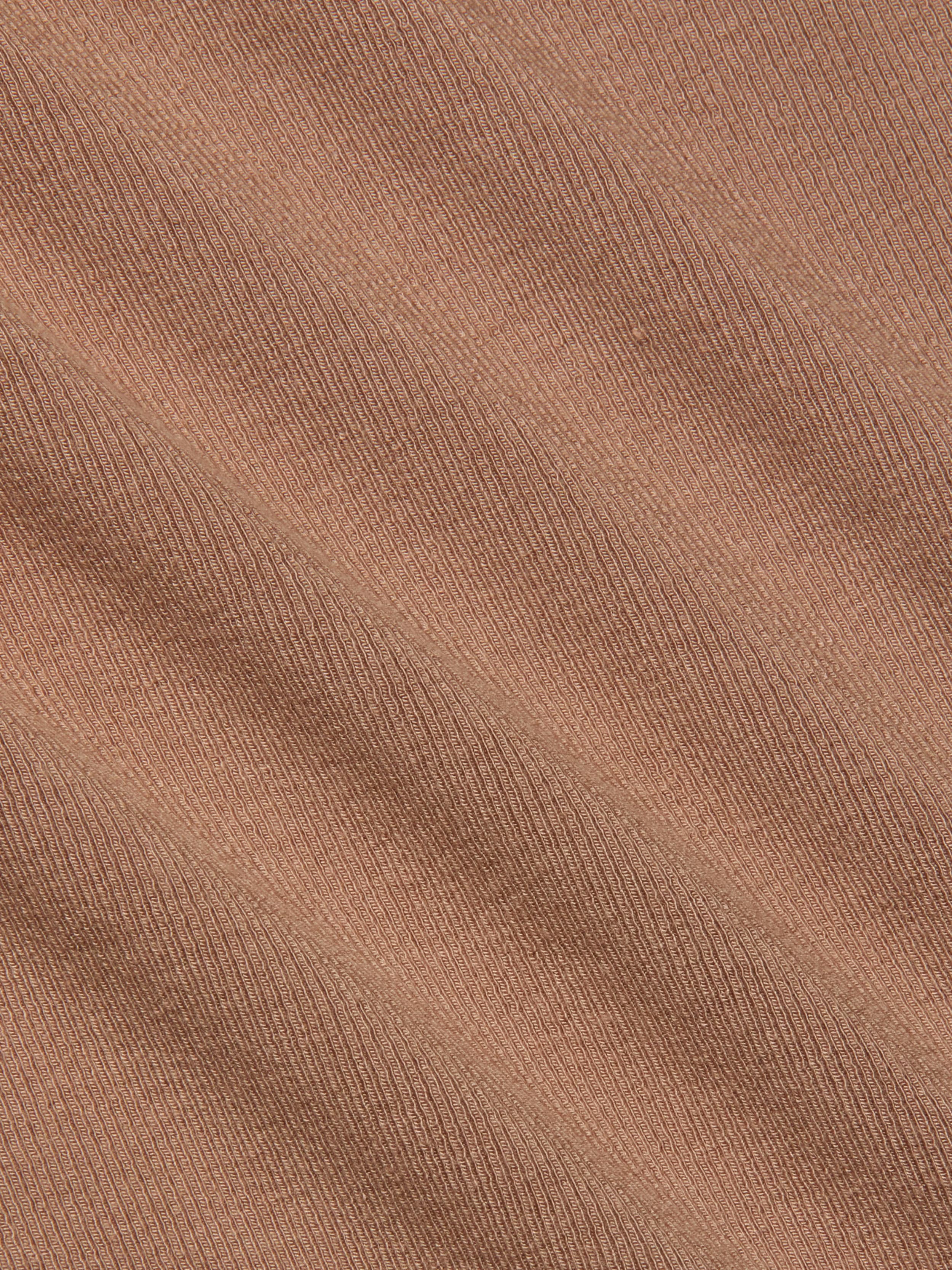 Close-up of the Wrenna Racerback Bodysuit’s light brown rib fabric, featuring fine, evenly spaced diagonal ridges and visible texture. The material showcases a subtle pattern with soft shadow effects across its surface.