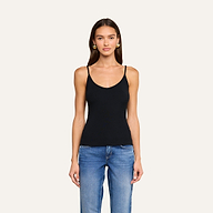 A woman with long brown hair, wearing a black ribbed Lunara Camisole and blue jeans, stands facing forward against a plain light background.