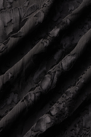 Close-up of the Christine Burnout Satin Dress by L'AGENCE in black, showcasing crinkle satin fabric with raised, irregular diagonal patterns and folds that add depth and tactile contrast.