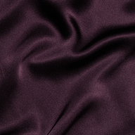 Close-up of smooth, dark purple satin fabric with gentle folds and a subtle sheen, evoking the elegant and luxurious texture featured in the Seridie Silk Slip Dress.