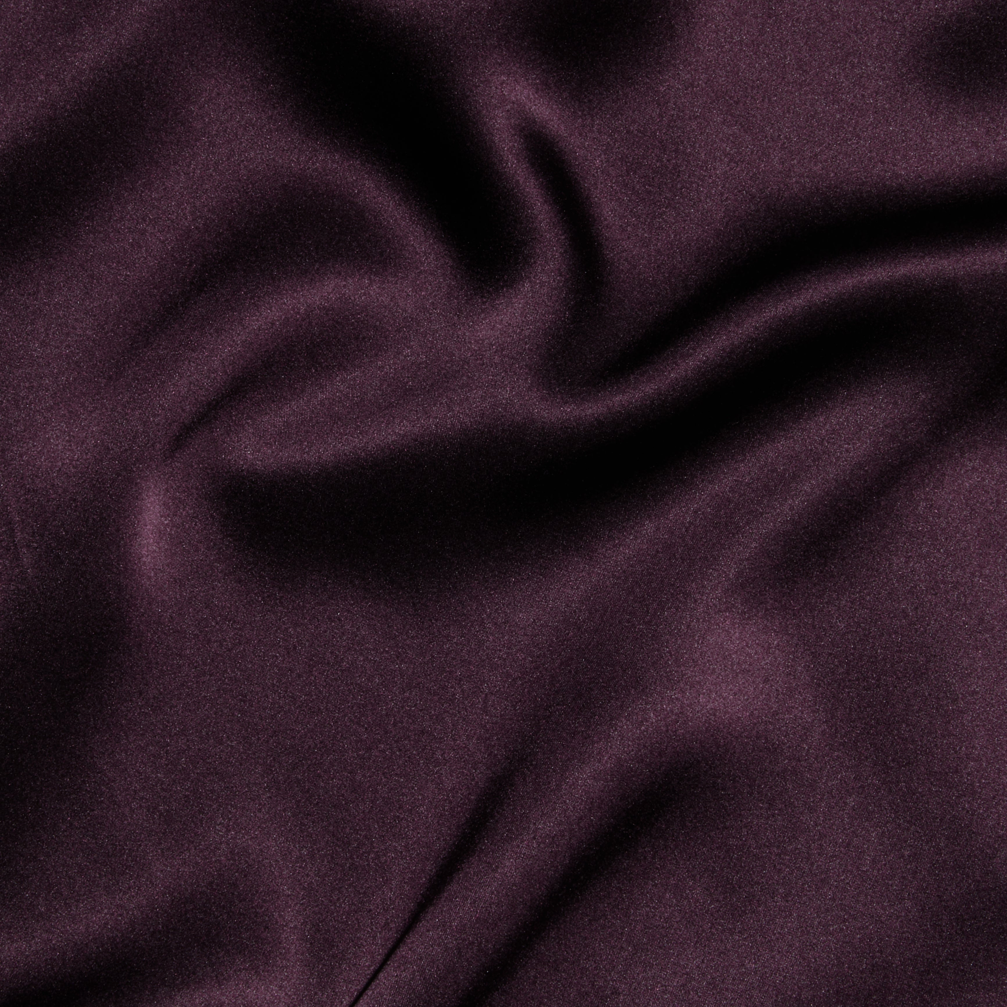 Close-up of smooth, dark purple satin fabric with gentle folds and a subtle sheen, evoking the elegant and luxurious texture featured in the Seridie Silk Slip Dress.