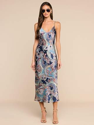 A woman wearing sunglasses and the Seridie Silk Slip Dress—a sleeveless, paisley-print silk slip dress with spaghetti straps—stands in high-heeled sandals against a neutral background.
