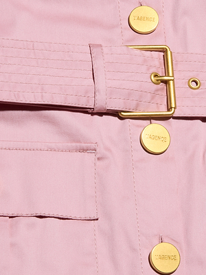 Close-up of the Noam Poplin Shirt Dress—a light pink utility jacket with a gold buckle belt, LAGENCE-stamped gold buttons, smooth fabric, and a front pocket.