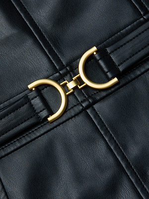 Close-up of the Halia Vegan Leather Dress by L'AGENCE, showcasing a central gold clasp with two symmetrical half-circle shapes joined by a small rectangular link.
