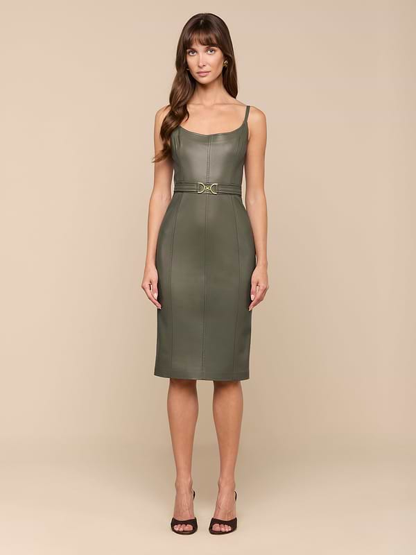 Une femme se tient debout sur un fond beige, de face, portant la robe Halia Vegan Leather Dress en smoky olive - une robe midi sans manches avec une taille ceinturée - associée à des sandales à talons noires.