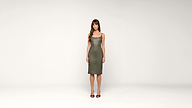 A woman with long brown hair stands facing forward, wearing a knee-length olive-green dress and black heels, against a plain white background.