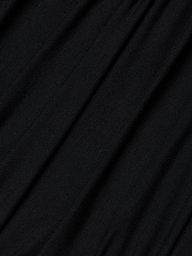 Close-up of the Paityn Shirred Dress’s smooth, black stretch jersey fabric with gentle folds and soft texture, creating subtle diagonal lines and shadows across the surface.