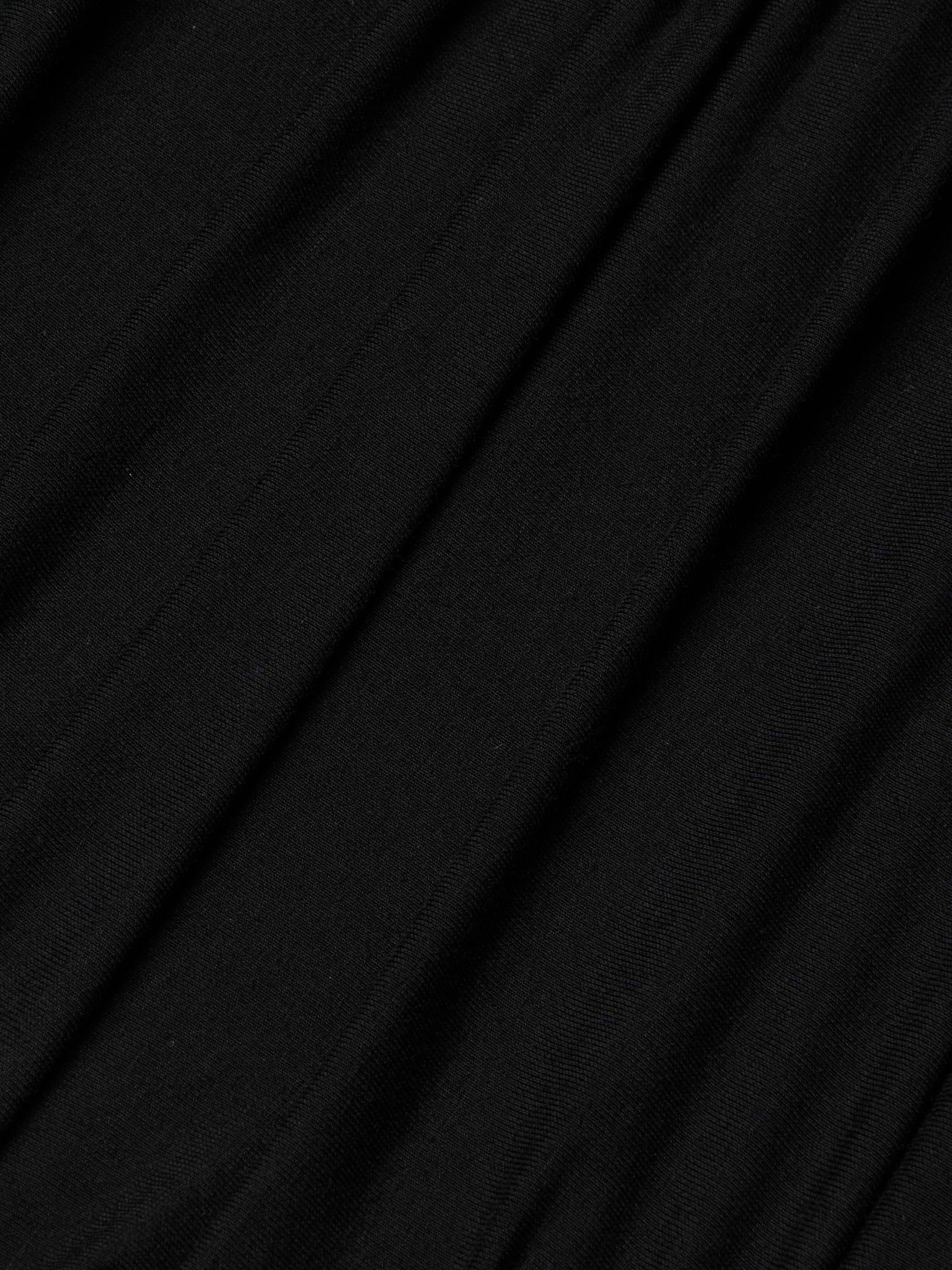 Close-up of the Paityn Shirred Dress’s smooth, black stretch jersey fabric with gentle folds and soft texture, creating subtle diagonal lines and shadows across the surface.