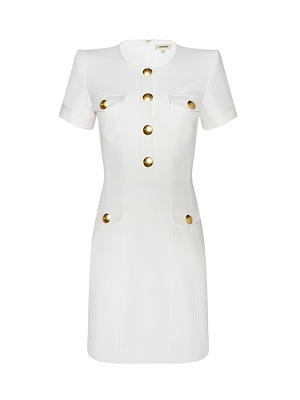 The Cori Mini Dress is a white, structured mini dress with short sleeves, a round neckline, gold-tone front buttons, and four flap pockets—two at the chest and two at the hips—each detailed with a gold button.