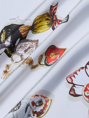 The Anika Slip Dress is crafted from white bias-cut satin with colorful prints—red hearts, ornate patterns, and ribbon-tied details—making it a smooth, standout choice for unique slip dresses or elegant evening wear.