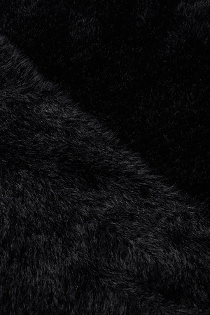 Close-up of the Antonella Crossover Sweater by L'AGENCE shows plush, dense black fibers with a subtle diagonal line—highlighting the sweater's soft, cozy texture and chic design.