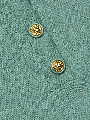 Close-up of the Ronda Knit Henley Top in lightweight green fabric, featuring two textured gold decorative buttons sewn onto its classic narrow Henley placket.