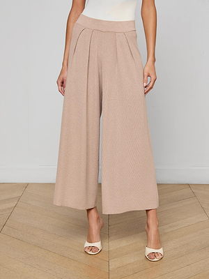 A person wearing Milly Knit Pant in high-waisted, light beige wide-leg style with cream open-toe heels is standing on a wooden floor against a plain light wall, visible only from the waist down.