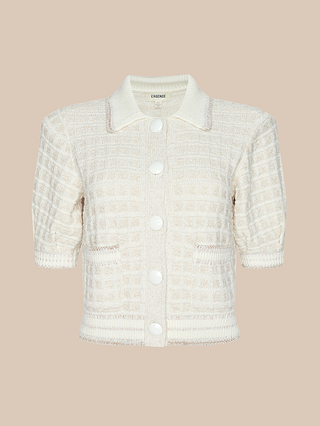 The Novalie Cardigan Top is a cream-colored, short-sleeve textured cardigan crafted from soft bouclé yarn, featuring large white buttons, two front pockets, and a collar, displayed on a beige background.