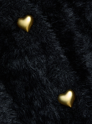 Two small golden heart buttons rest on the textured black knit of the Harriet Cardigan by L'AGENCE.