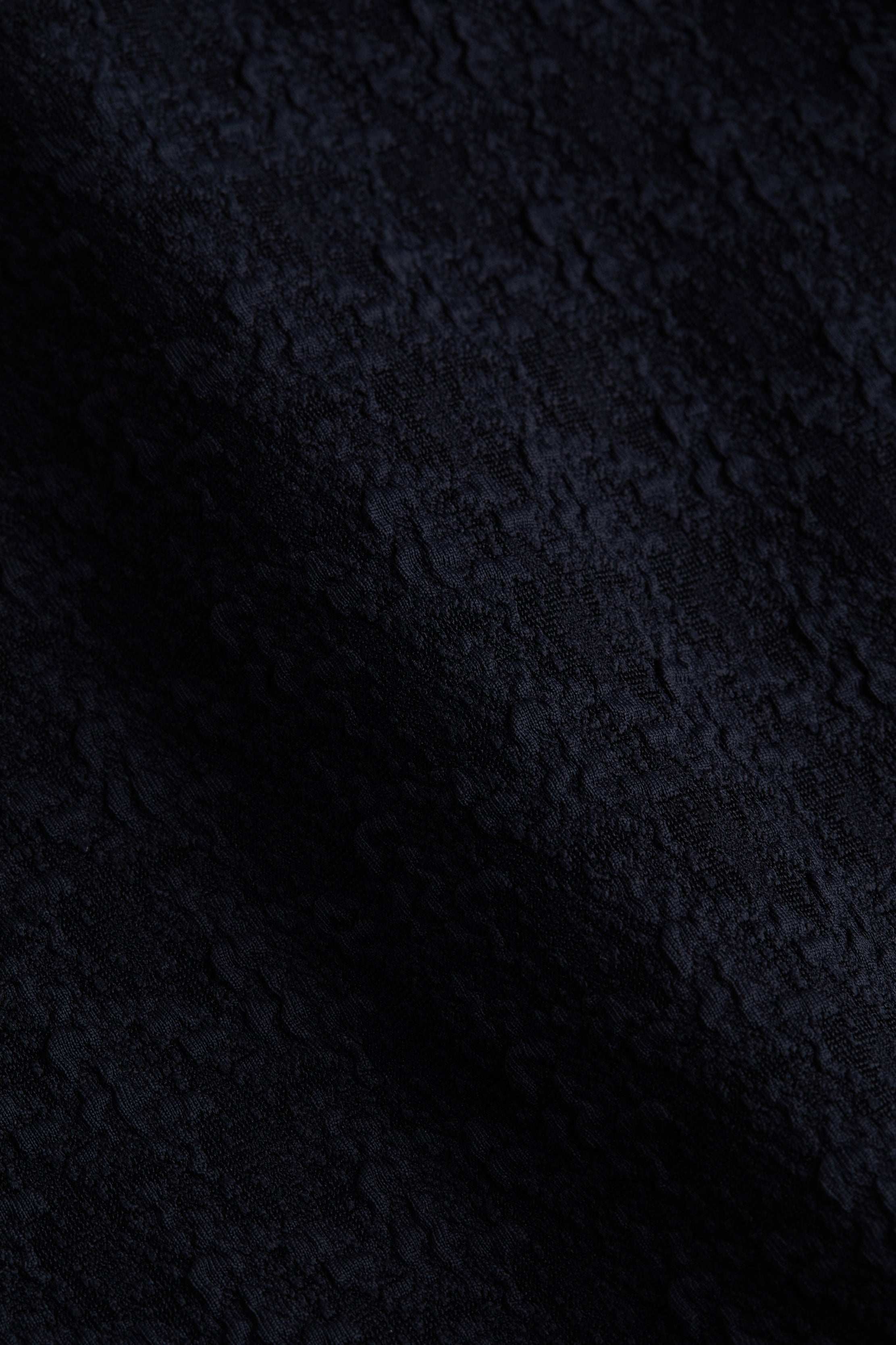 Close-up of the Alexandria Bikini Top in black, featuring textured bouclé fabric with subtle wavy patterns and a slightly raised, tactile surface.
