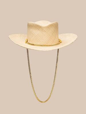 The Zamora Cowboy Hat by Gladys Tamez Millinery features woven straw, a wide brim, and gold chains draped from each side, set against a plain beige background.