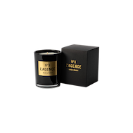 A black Ambre Soleil candle, adorned with gold accents and matching label, is displayed next to its coordinating black and gold box on a light background. This sophisticated candle is part of our hand-poured collection, thoughtfully crafted for a clean, even burn.