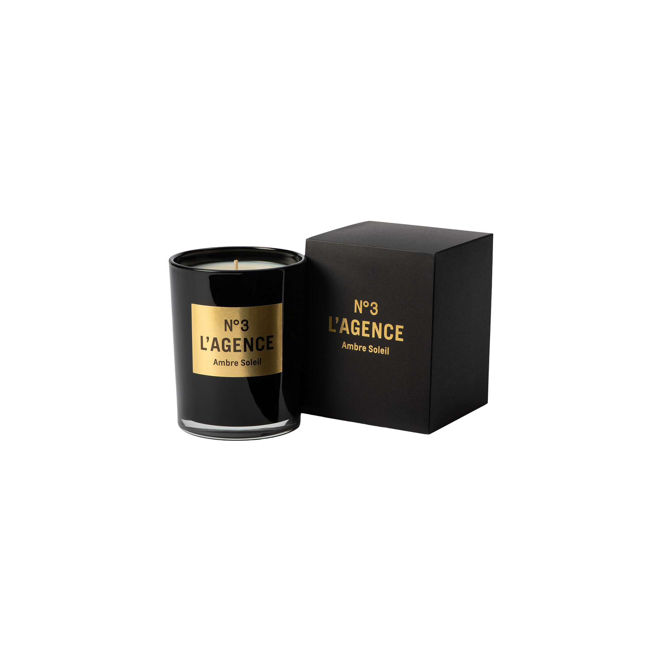 A black Ambre Soleil candle, adorned with gold accents and matching label, is displayed next to its coordinating black and gold box on a light background. This sophisticated candle is part of our hand-poured collection, thoughtfully crafted for a clean, even burn.