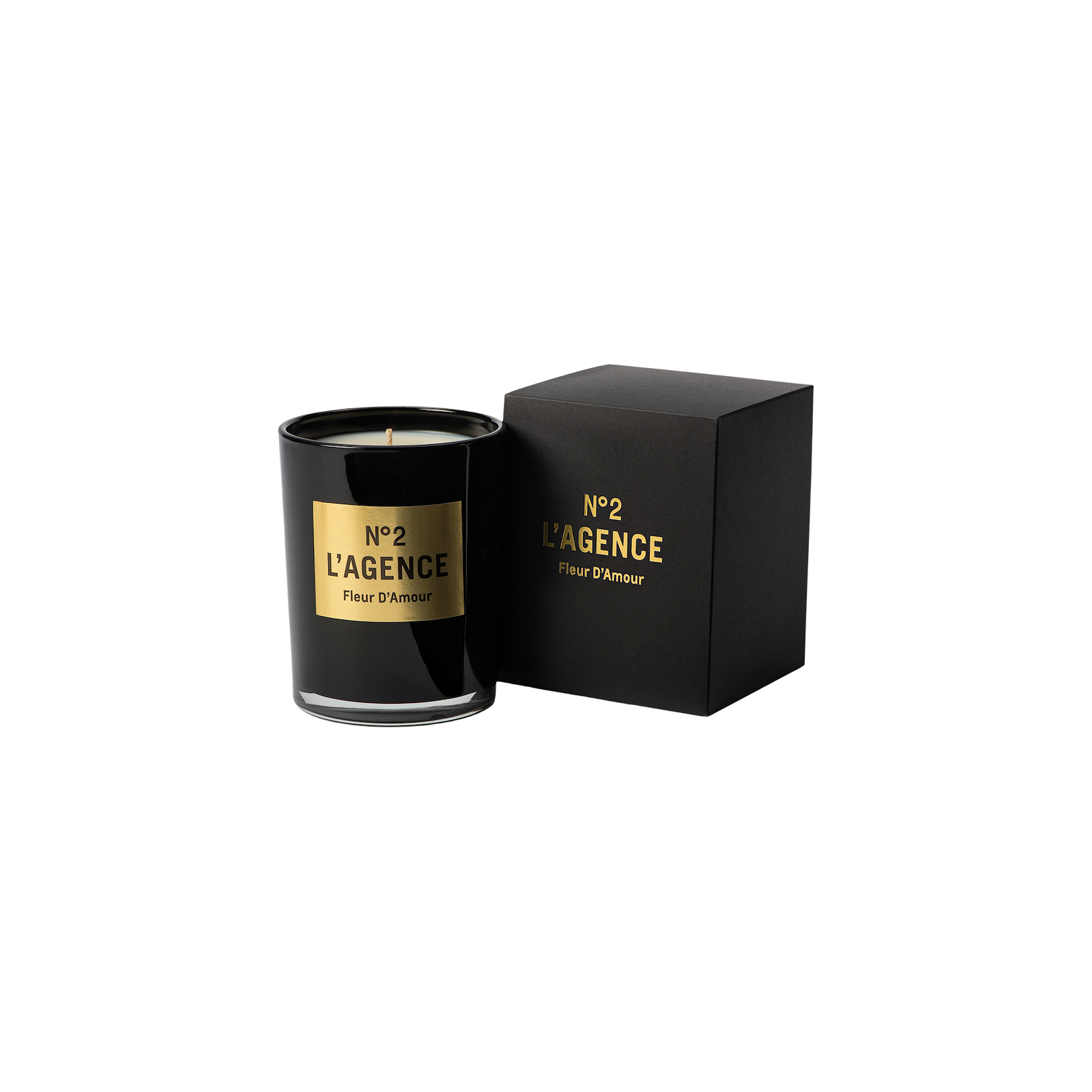 A black glass Fleur D’Amour candle, labeled No 2 LAGENCE, rests beside its coordinating black and gold box on a white background, highlighting the sophistication of this hand-poured candle crafted from premium soy-blend wax.