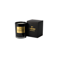 A black glass candle labeled Suède et Santal, made with soy-blend wax, sits next to its matching black and gold box on a plain white background.
