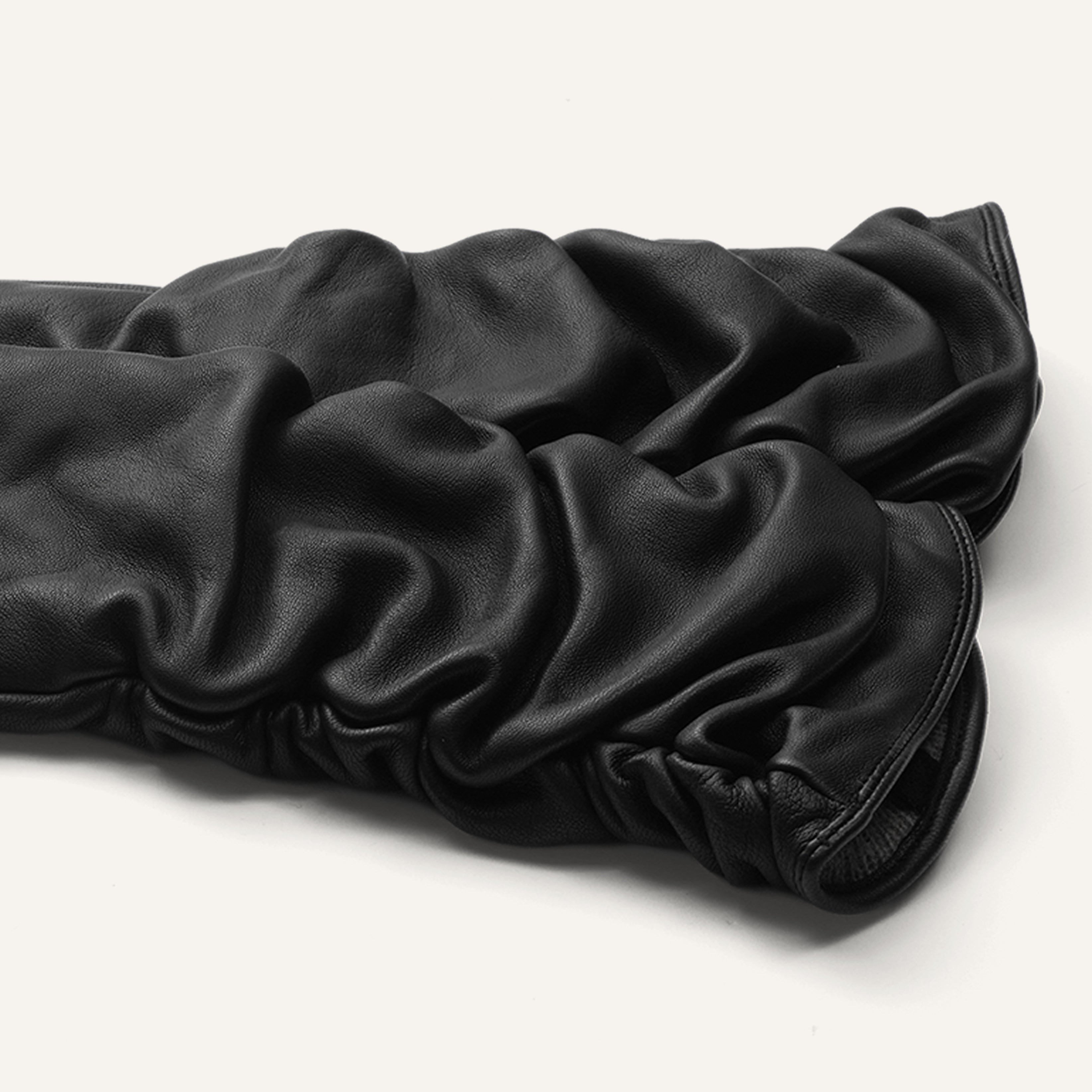 A pair of elegant, long black gloves crafted from ruched leather are displayed on a white background.