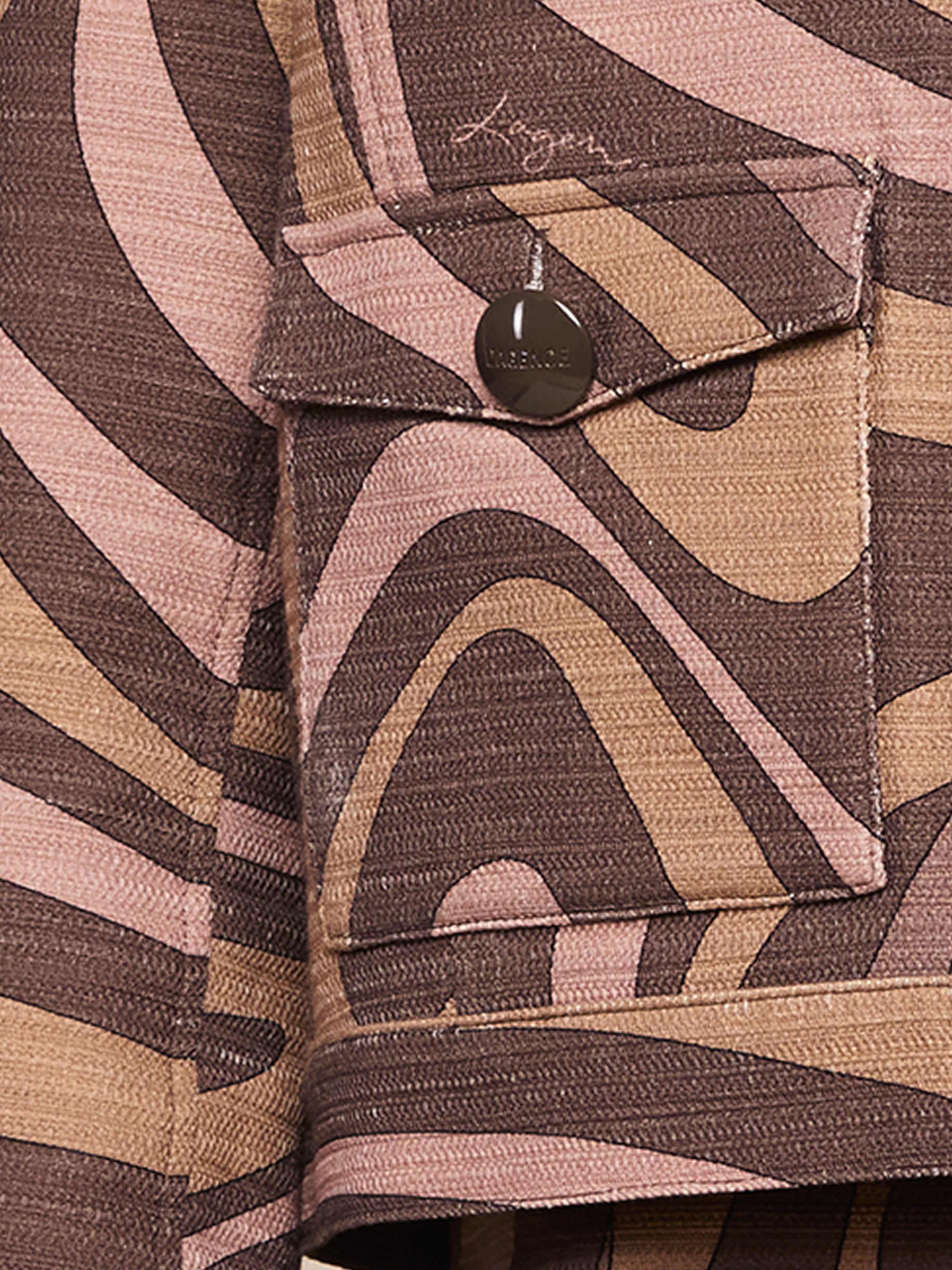 A close-up of a fabric pocket with a metallic button. The fabric features a wavy, abstract pattern in shades of brown, beige, and pink.