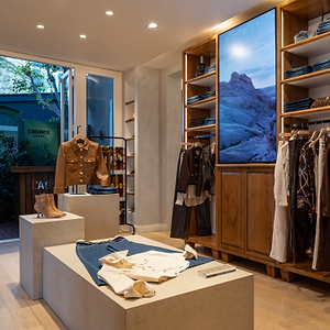 Interior of a clothing store with wooden shelves and display tables.