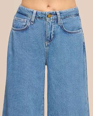 A person wearing high-waisted, light blue denim jeans with wide legs. The jeans have front pockets and a button closure. Only the lower torso is visible against a plain background.