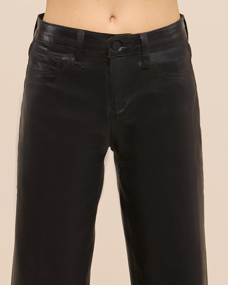 A person wearing high-waisted, black, shiny pants with front pockets and belt loops. The image is cropped from the waist to the mid-thigh.