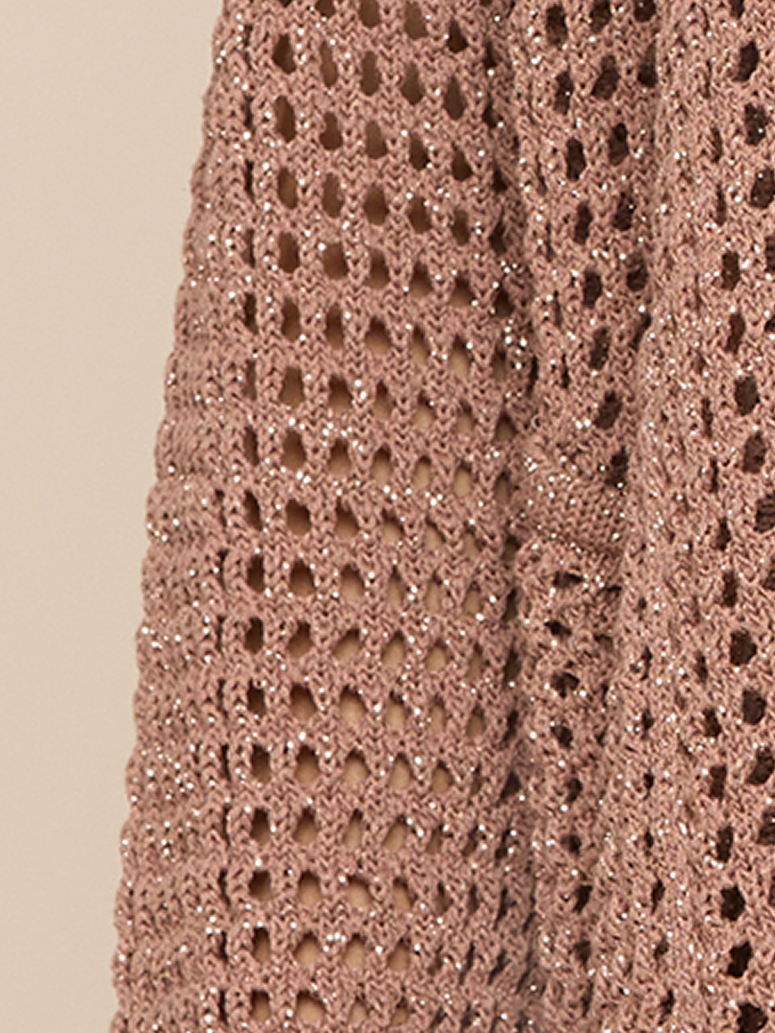 Close-up of a knitted fabric in a light brown color with metallic threads, featuring an open, mesh-like pattern. The texture appears soft and shimmery, with visible holes between the stitches.