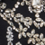 A close-up of sparkling, silver and crystal jewelry pieces arranged on a black surface, including floral and geometric designs.