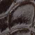 Close-up of a dark, textured surface with a pattern resembling overlapping scales or tiles, possibly from leather or reptile skin. The surface appears shiny and slightly rough.