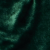 A close-up of dark green, velvet-like fabric with soft folds and a slightly shiny texture, creating an abstract, rich appearance.