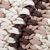 Close-up of a crocheted fabric with chunky yarn in cream, brown, and taupe colors, arranged in diagonal stripes. The texture appears soft and thick.