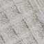 Close-up view of tire tracks in fresh, white snow on a rough, brown surface, showing parallel lines with patches of underlying ground visible through thin snow coverage.