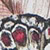 Close-up of a butterfly wing displaying intricate patterns with black, white, and red spots. The image shows detailed textures and vibrant colors.