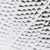 Close-up of a textured surface with a repeating pattern of small, dark, scale-like shapes on a shiny, light background, resembling snake or reptile skin.