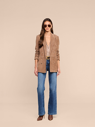 Wearing the Arabell Romper, a woman stands against a beige background facing forward with her hands at her sides—embodying a warm-weather essential look perfect for any stylish occasion.