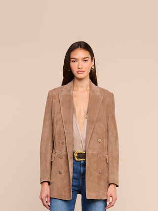 Wearing the Arabell Romper, a woman stands against a plain beige background.