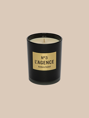 The Ambre Soleil candle features black glass, beige soy-blend wax, and a label reading N°3 LAGENCE Ambre Soleil, hand-poured for Southern California elegance, displayed on a plain beige background.