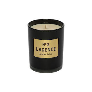 A hand-poured Ambre Soleil candle, featuring a black jar with a gold label that reads Nº 3 LAGENCE and filled with light-colored, unused soy-blend wax. This elegant candle brings sophistication to your space and provides a long-lasting burn for extended enjoyment.