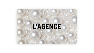 A backdrop of lustrous white pearls of assorted sizes features “L’AGENCE” in bold black caps at the center, showcasing the L'AGENCE Gift Card delivered via email.