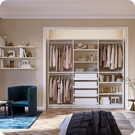 Open white reach-in with a center 4-drawer bank, symmetrical double hanging, & shelving for shoes & handbags in a bright bedroom with a blue velvet chair