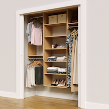 Natural oak 64.5-inch woodgrain Vista Total Closet Kit in a reach-in closet with dresses, shoes, and handbags