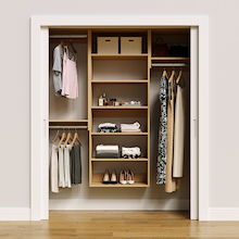 Natural oak 64.5-inch woodgrain Vista Total Closet Kit, front view in a reach-in closet, holding dresses
