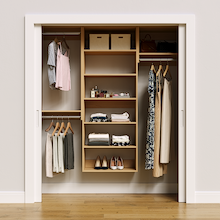 Natural oak 67.5-inch woodgrain Vista Total Closet Kit, front view in a reach-in closet, holding dresses